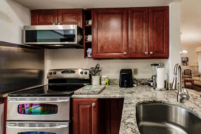 kitchen with sink, stainless steel appliances, and light stone counters