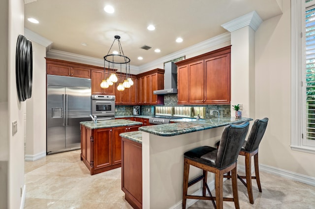 kitchen with a center island, decorative light fixtures, a kitchen bar, stainless steel appliances, and dark stone countertops