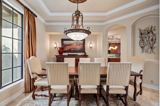 dining space featuring a tray ceiling, crown molding, and a notable chandelier