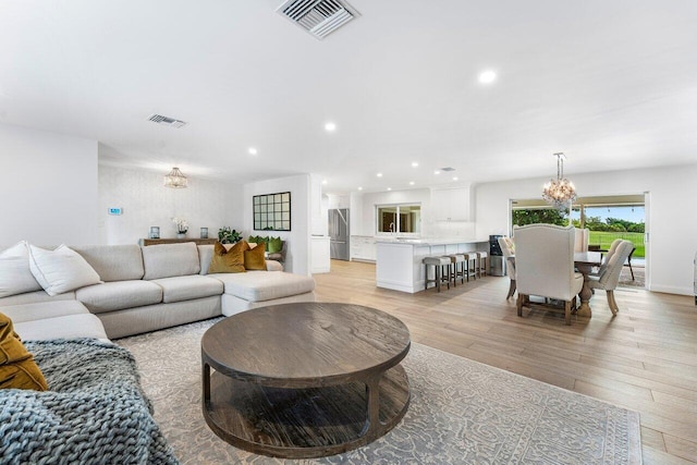 living room featuring a notable chandelier and light hardwood / wood-style flooring