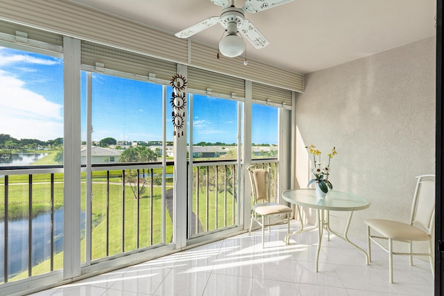 sunroom / solarium featuring ceiling fan and a water view