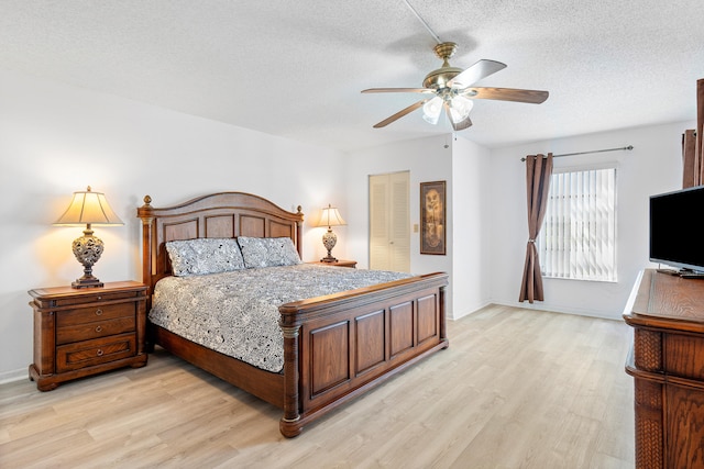 bedroom featuring light wood-type flooring, a textured ceiling, ceiling fan, and a closet