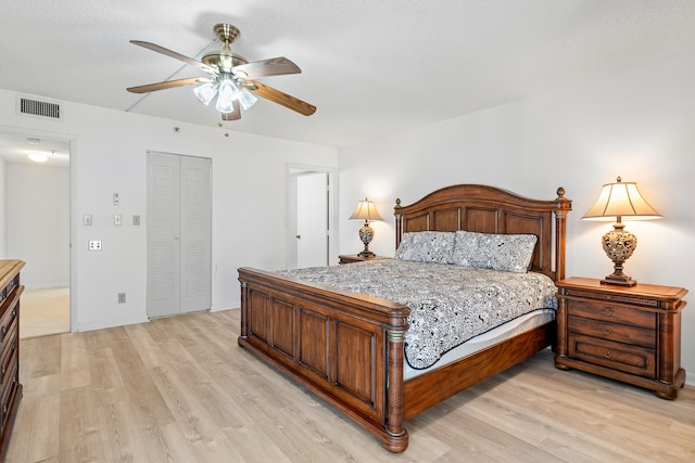 bedroom featuring light hardwood / wood-style flooring, a closet, ceiling fan, and a textured ceiling