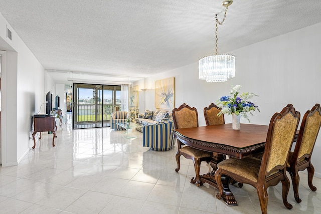 tiled dining room with an inviting chandelier and a textured ceiling