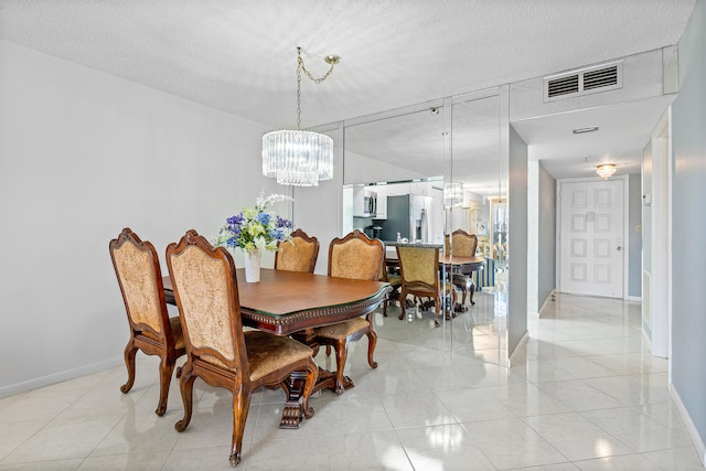 tiled dining room with a notable chandelier and a textured ceiling