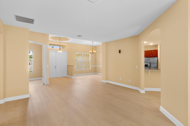 unfurnished room featuring an inviting chandelier and light hardwood / wood-style flooring