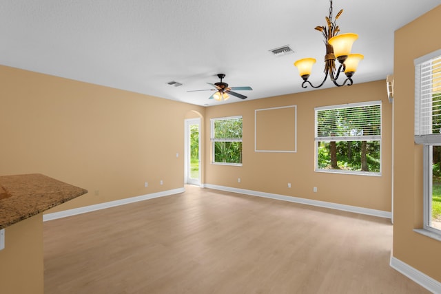 interior space featuring a wealth of natural light, ceiling fan with notable chandelier, and light wood-type flooring