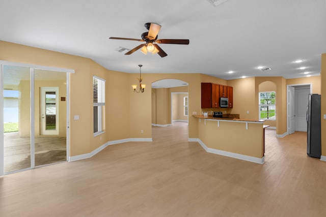 kitchen with black refrigerator, plenty of natural light, kitchen peninsula, and light wood-type flooring