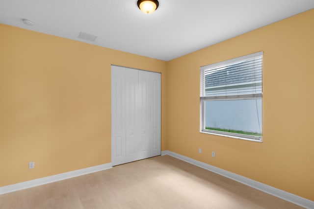 unfurnished bedroom featuring light hardwood / wood-style flooring and a closet