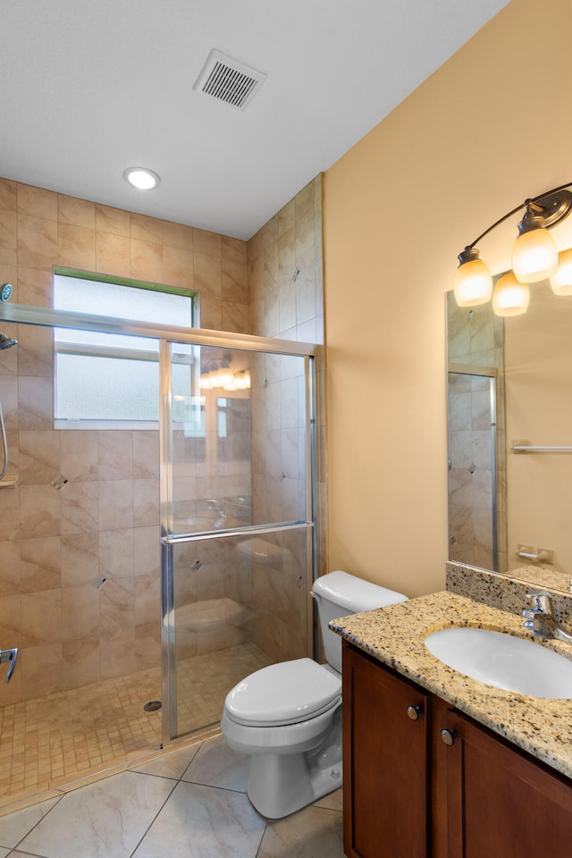 bathroom with vanity, toilet, tile patterned floors, and a shower with door