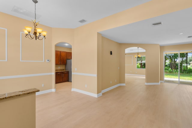 unfurnished room with light wood-type flooring and a chandelier