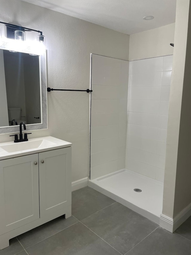 bathroom with tile patterned flooring, a shower, and vanity