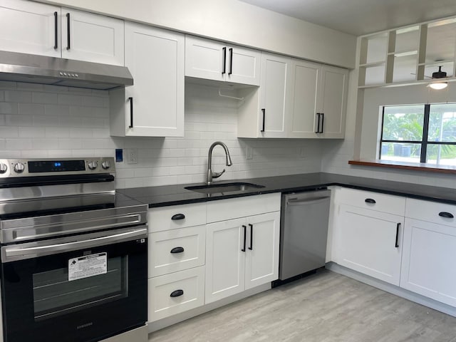 kitchen featuring white cabinets, light hardwood / wood-style flooring, stainless steel appliances, sink, and tasteful backsplash