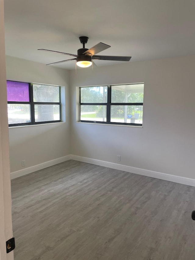 empty room featuring ceiling fan, a wealth of natural light, and hardwood / wood-style flooring