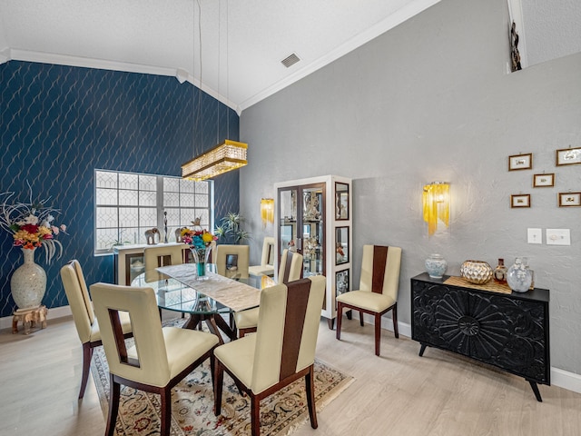 dining space featuring crown molding, vaulted ceiling, and light hardwood / wood-style floors