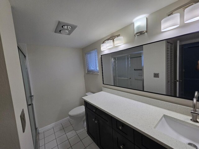 bathroom with vanity, toilet, tile patterned floors, and a shower with door