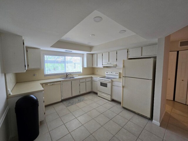 kitchen featuring white appliances, light tile patterned floors, a raised ceiling, and sink