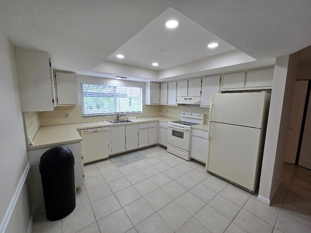 kitchen featuring a tray ceiling, light tile patterned floors, white appliances, and sink