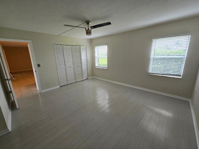 unfurnished bedroom with hardwood / wood-style floors, ceiling fan, a closet, and a textured ceiling