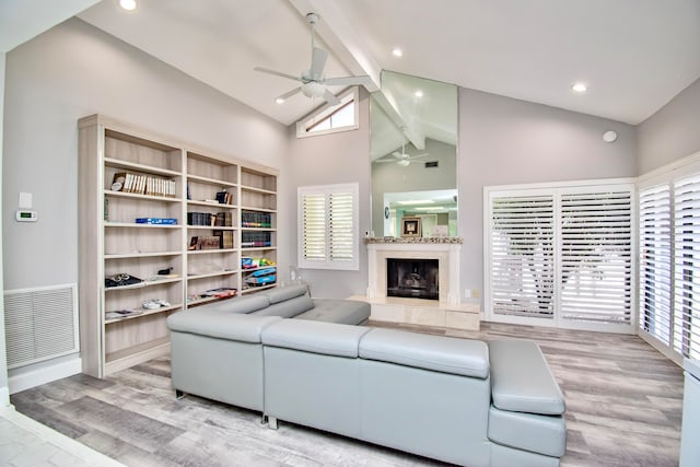 living room with a fireplace, beamed ceiling, a healthy amount of sunlight, and ceiling fan