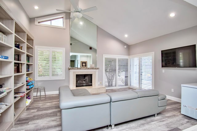 living room featuring high vaulted ceiling, ceiling fan, a high end fireplace, and wood-type flooring