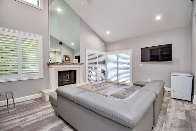 living room featuring a fireplace, high vaulted ceiling, and light hardwood / wood-style flooring