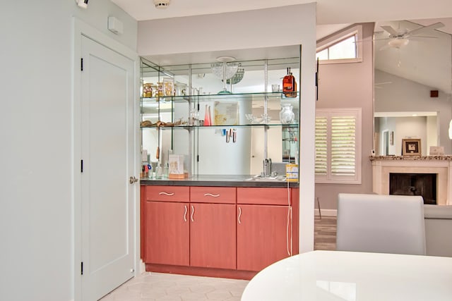 bar with vaulted ceiling, light tile patterned flooring, sink, and ceiling fan