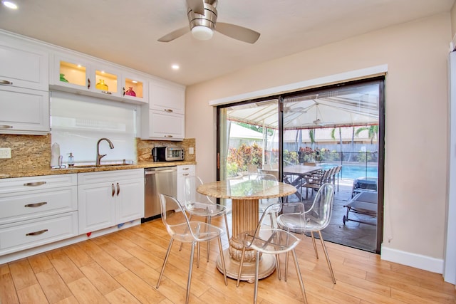 kitchen with ceiling fan, white cabinetry, stainless steel dishwasher, and light stone countertops