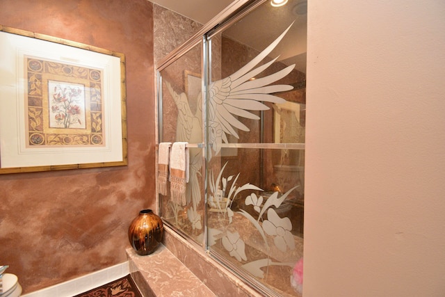 bathroom featuring a shower with shower door and toilet