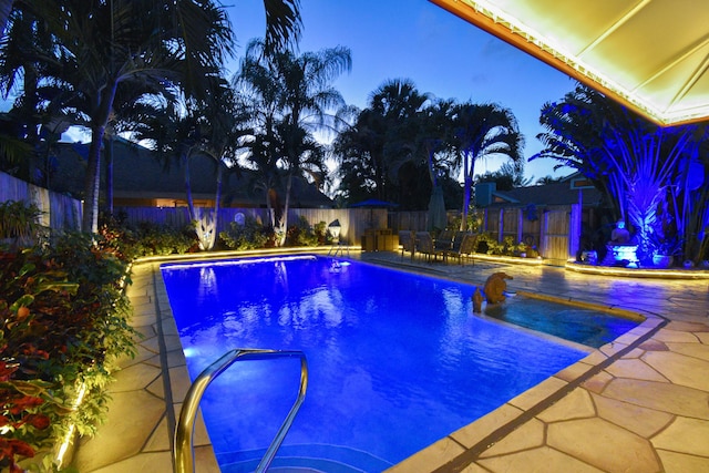 pool at dusk featuring a patio and pool water feature