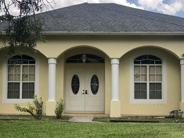 entrance to property featuring a lawn, french doors, and a porch