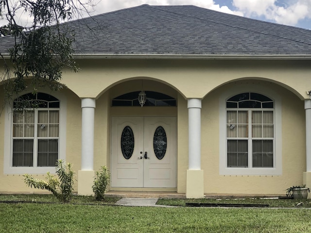 property entrance featuring stucco siding and a shingled roof