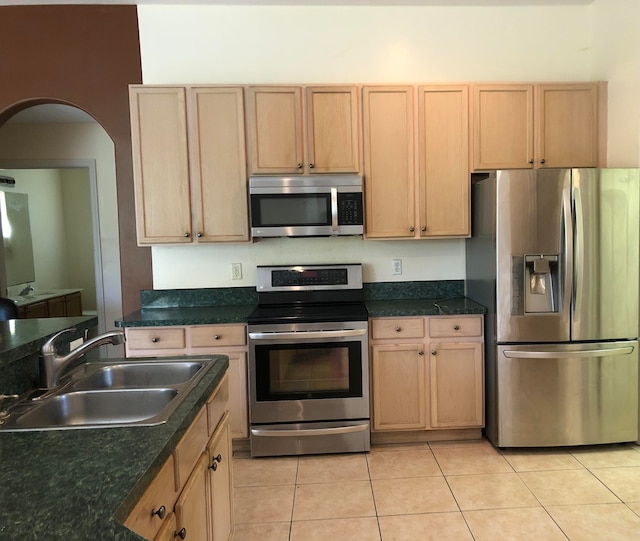 kitchen with appliances with stainless steel finishes, light tile patterned floors, sink, and light brown cabinets