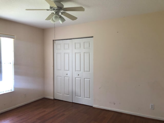 unfurnished bedroom with a closet, ceiling fan, and dark hardwood / wood-style floors