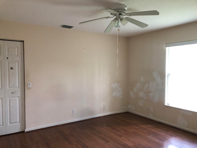 empty room with dark hardwood / wood-style flooring, plenty of natural light, and ceiling fan