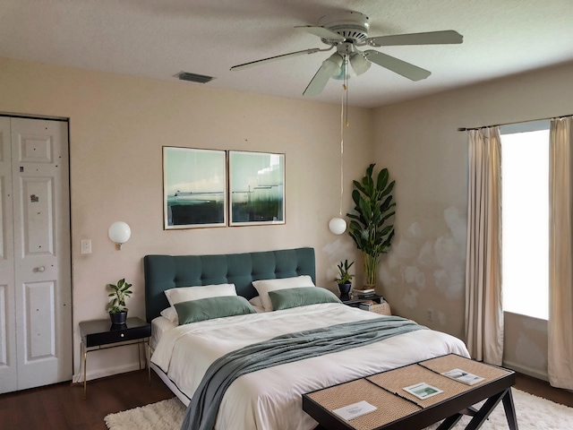 bedroom with multiple windows, hardwood / wood-style floors, ceiling fan, and a closet