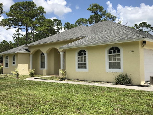 single story home featuring stucco siding, roof with shingles, and a front lawn