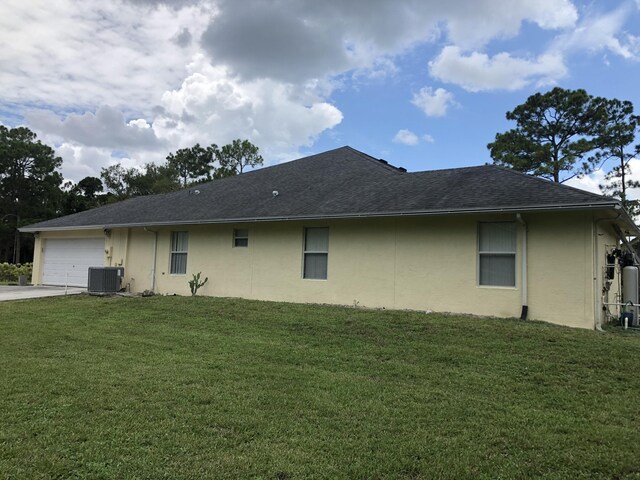 back of house featuring a yard, a garage, and central air condition unit