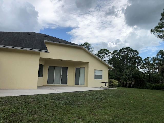 back of property with a yard and a patio