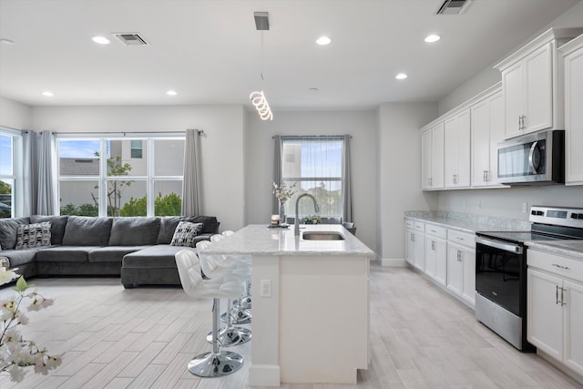 kitchen with white cabinets, appliances with stainless steel finishes, plenty of natural light, and sink