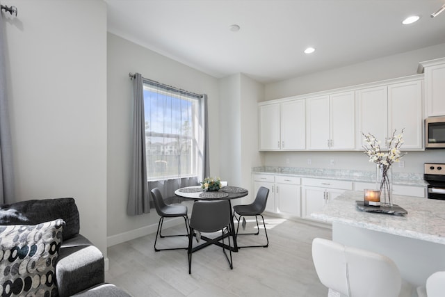 kitchen with white cabinetry, light stone countertops, light hardwood / wood-style flooring, and stainless steel appliances