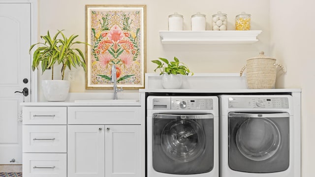 clothes washing area with cabinets, washer and dryer, and sink