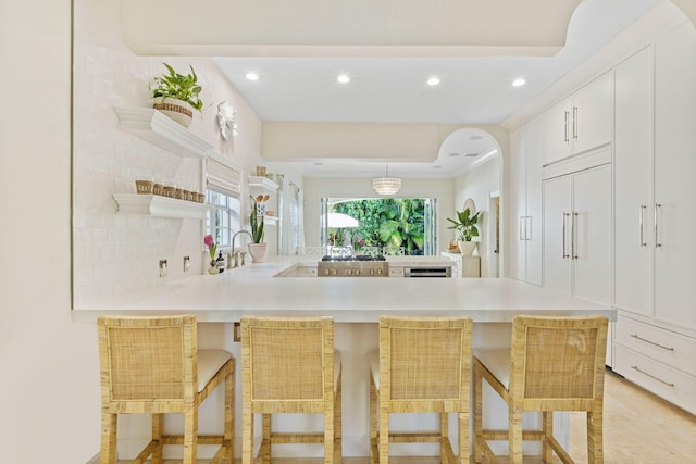 kitchen featuring white cabinets, a breakfast bar area, kitchen peninsula, and sink