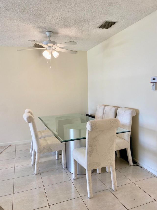 tiled dining room featuring a textured ceiling and ceiling fan