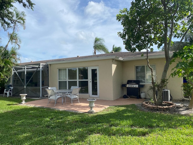 rear view of property featuring glass enclosure, central air condition unit, a yard, and a patio area