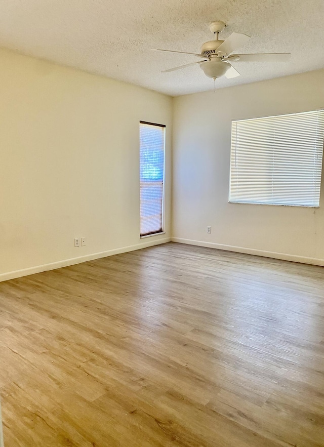 spare room with light wood-type flooring, ceiling fan, and a textured ceiling