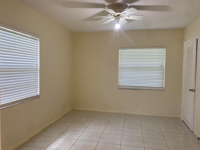 empty room with a textured ceiling, ceiling fan, and light tile patterned flooring