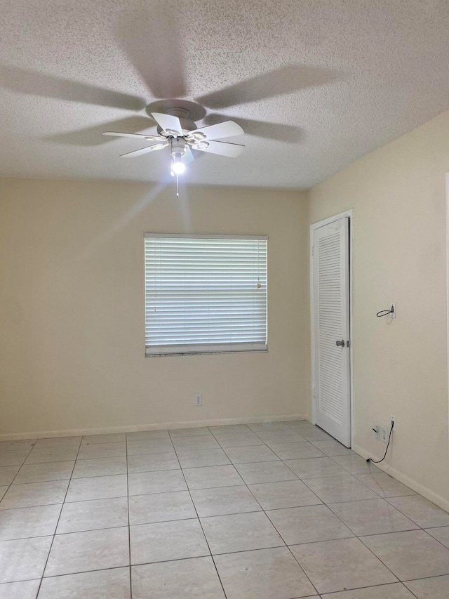 tiled spare room with ceiling fan and a textured ceiling