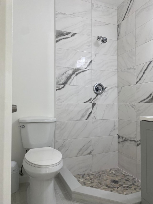 bathroom with tiled shower, vanity, and toilet