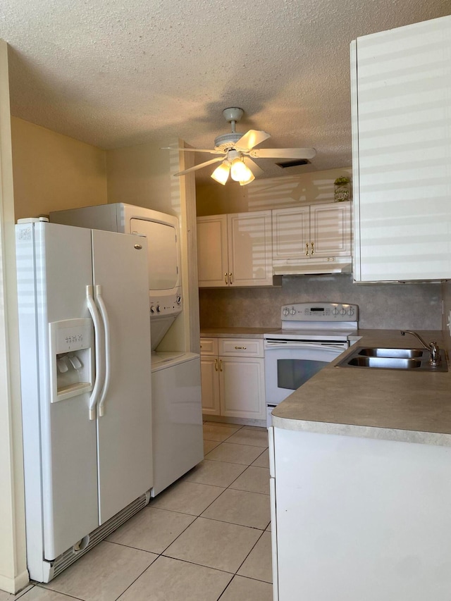 kitchen with a textured ceiling, stacked washer and clothes dryer, white appliances, sink, and ceiling fan